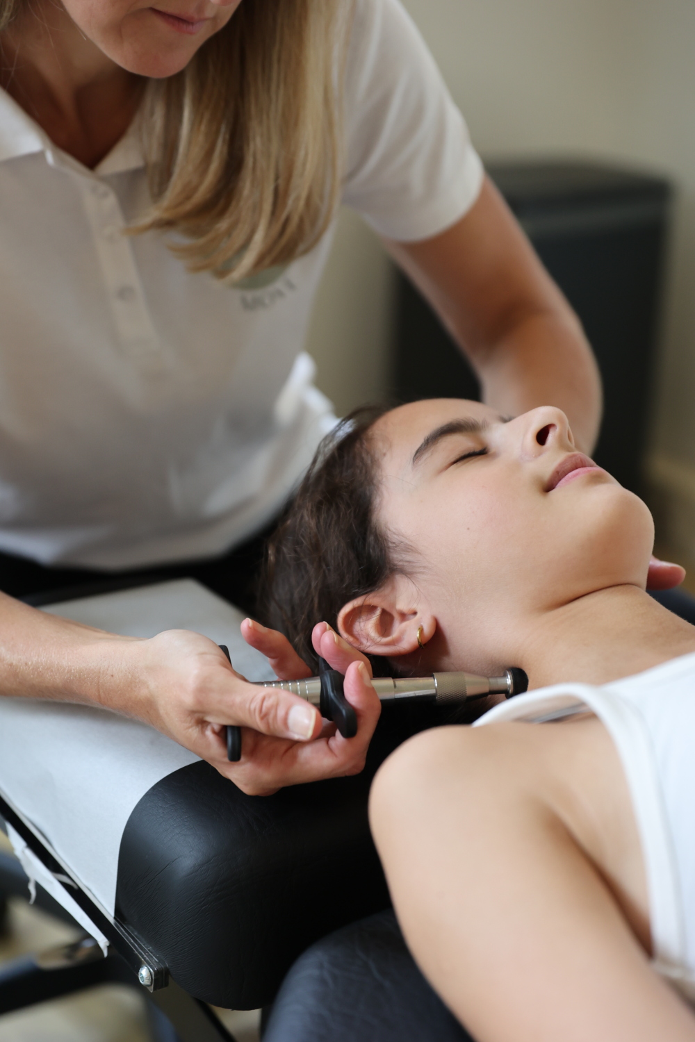 Chiropractor behandelt de nek van een patient met een activator apparaat